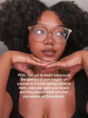 The cover image shows a close-up of a woman's face, captured from a slightly low angle filling most of the frame. Her dark hair is styled in curly afro. She wears light-framed glasses. Her hands are positioned below her face, with her fingertips touching, creating a thoughtful pose. The background is blurred, suggesting an indoor setting.