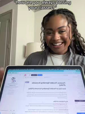 A woman with dark hair and braids smiles widely, looking towards the camera. The text overlay reads, "how are you always passing your classes?" The woman is wearing a light grey top and is set in a room with a lamp and a laptop displaying a document.