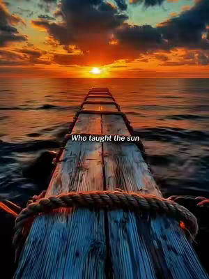 A scenic image of a wooden pier extending into the ocean towards a vibrant sunset. The sky is filled with colorful clouds, and the sun is positioned just above the horizon, casting a warm glow. The wooden planks of the pier are weathered and textured, with a rope running along the edge.