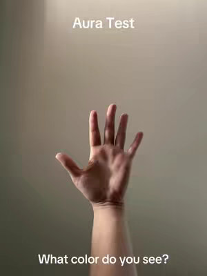 The image features a hand with an open palm, set against a gradient background that transitions from a light beige at the top to a slightly darker shade towards the bottom. The text overlay at the top reads 'Aura Test' in a clean, sans-serif font. At the bottom of the image, the text 'What color do you see?' posed as a question is overlaid in the same font. The composition highlights the hand as the central element for viewers' interaction.
