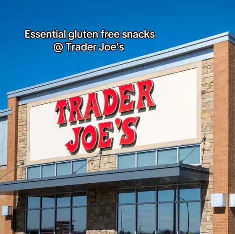 The cover image shows the exterior of a Trader Joe's store with the store's sign prominently displayed. Above the sign a text overlay reads, 'Essential gluten free snacks @ Trader Joe's'. The sky is blue and forms the background. The Trader Joe's sign is red and white.