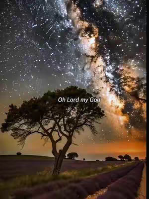 An eye-level shot showcases a tranquil landscape under a starlit sky. A prominent tree, its branches reaching upwards, stands in the foreground, silhouetted against a twilight sky ablaze with stars. The text overlay "Oh Lord my God" appears above the tree. The sky transitions from a dark blue with many stars to a golden orange at the horizon. The ground features gentle hills with more trees and a path in the lower part of the image.