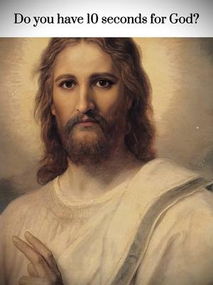 The image features a portrait of Jesus. He has long brown hair and a beard. He is wearing a white robe, and his right hand is raised in a gesture of peace. The background is a soft, blurred light.