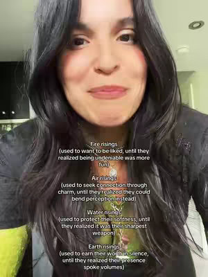 A woman with long black hair is the central focus of the image. She appears to be in her late twenties to early thirties, with light skin and dark eyes. Her expression is a gentle smile, as if she's about to speak. The background seems to be a typical indoor setting, with a wall and some out-of-focus objects providing a natural backdrop. A text overlay with various phrases related to astrology is present on top of the image. The text is in a clean, sans-serif font and adds context to the video's theme, giving an educational feel.