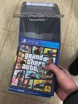 A hand holds a PS4 case for the video game Grand Theft Auto V in front of a blue and gray container. The game case is in focus, showing various character portraits from the game and the game's logo. Above the game case, in the background, a container with a lid is partially visible. Text overlay appears at the top.
