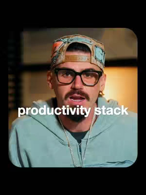 A man with a beard, glasses, and a baseball cap looks towards the camera with a focused expression. Below him is the text overlay, "productivity stack". The background suggests an interior setting, possibly a studio, with the color palette leaning towards neutral tones.