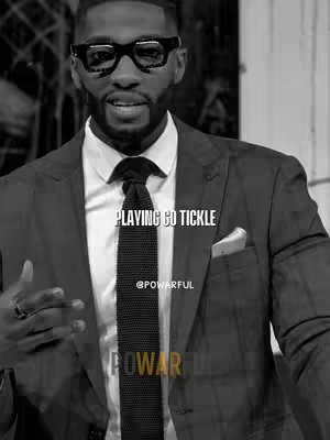 A black and white image featuring a man in a suit with a tie, wearing glasses, facing the camera, and speaking. Text overlays are visible in multiple areas of the image.