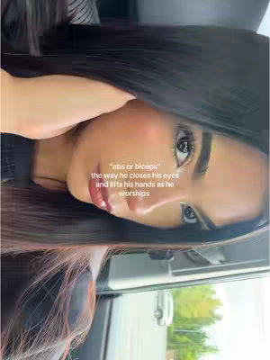 A selfie-style shot focusing on the face of a woman. She has long, dark hair and is angled slightly towards the right of the frame. The background includes the inside of a car. Overlaid text appears in white font to the left of her face.