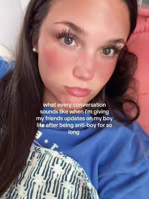 A selfie-style image featuring a young woman with long dark hair, wearing a blue top and resting on a pink surface. The woman has a serious expression, and text overlays the image.