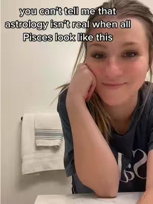 A woman with blonde hair is leaning on her hand in what appears to be a bathroom, a towel rack is visible in the background, and text overlays that reads, 'you can't tell me that astrology isn't real when all Pisces look like this'.