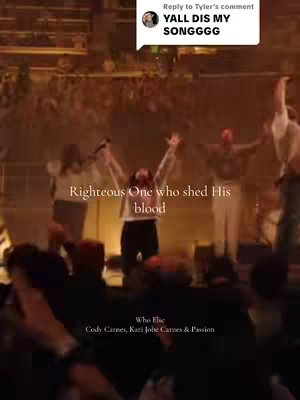 A live performance stage with musicians. The main focus is on a person with their hands raised with other people on the stage wearing white. The overall scene is dimly lit, with stage lights. In the top right is a comment overlay.