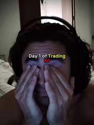 A man with dark hair and a beard is shown with their eyes covered by their hands. Above his head, text overlaid on the image reads 'Day 1 of Trading', and the dollar sign. The background is dark and blurry.