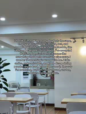 The image shows a text-heavy overlay on what appears to be a public seating area. The text covers most of the frame, expressing feelings of sadness and a lack of self-worth. In the background, there are tables and chairs, suggesting an indoor setting. The lighting is soft and the overall composition of the photo is straightforward.
