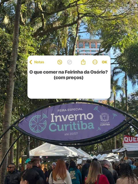 An eye-level shot captures a busy outdoor scene at a winter market. Lush trees with green foliage frame the top and left side. Within the frame, there's a large, arched sign that reads "FEIRA ESPECIAL Inverno Curitiba," with 'Inverno' highlighted in large, bold letters, suggesting a special winter event in Curitiba. Below the sign, people walk around, with white tents and fair stalls visible in the background. At the top left, a white note-shaped box contains the question "O que comer na Feirinha da Osório? (com preços)". The image suggests a promotional image.