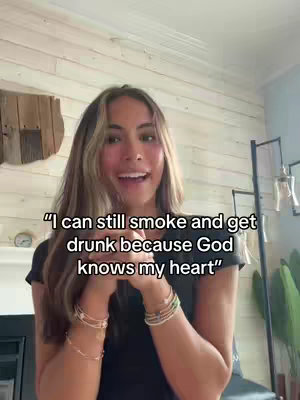 A young woman with long brown hair smiles and looks towards the camera. She is wearing a dark top and multiple bracelets. The background is a light-colored wall with a wooden texture. Text overlayed on the image reads: "I can still smoke and get drunk because God knows my heart".