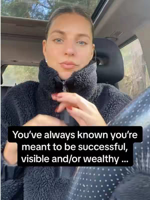 A woman with light skin and light hair framed in an indoor setting, possibly a car. She is wearing a dark, fuzzy jacket. The text overlay on the image reads, 'You've always known you're meant to be successful, visible and/or wealthy...'