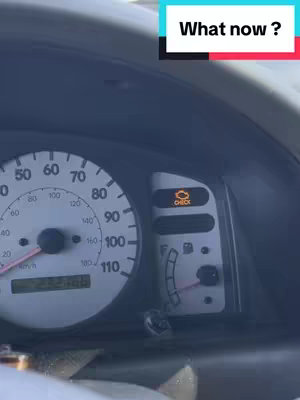 The image shows the dashboard of a car with the check engine light illuminated, indicating a potential problem. A text overlay asks, "What now?"
