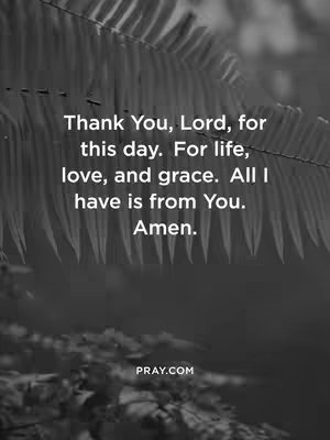 A grayscale image features a close-up view of a plant in the upper left, slightly out of focus, framing a centered vertical block of white text. The text conveys a message of gratitude and faith in a simple, elegant font, set against a soft, blurred background. At the bottom of the image is the logo "PRAY.COM"