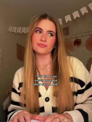 A woman with long blonde hair is the central focus, slightly angled and looking upwards. She is wearing a striped sweater and several rings. Overlaid text at the bottom reads, "but God can never love me after what I did." The background is dimly lit, with a few decorations visible.