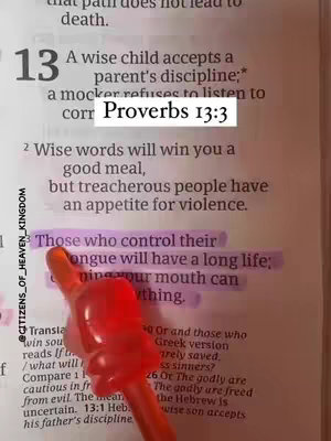 The image shows an open Bible with a highlighted passage. A red cartoon hand-shaped pointer is pointing towards the text. The colors are warm, and the composition is well-lit, focusing on the highlighted Bible verse.