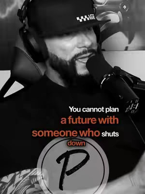 A black and white image featuring a man with a beard wearing a cap and headphones, speaking into a microphone. Text appears on the lower portion of the image.