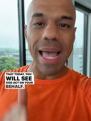 A bald Black man with an orange shirt is speaking directly to the camera. Text is overlaid at the bottom.