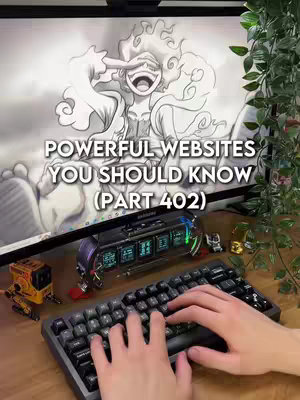 The image shows a person's hands typing on a black keyboard. Behind it is a computer monitor displaying a sketch of a cartoon character. On the desk are a digital clock, figurines, and other tech accessories.