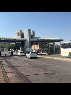 The cover image shows a street scene with a university entrance gate. White cars and a bus are queued at the gate. The sky is clear and blue.