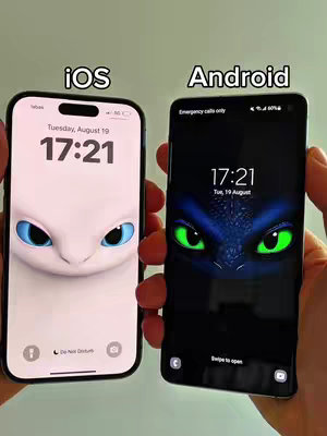 Two smartphones display wallpapers of a dragon-like character. The phone on the left is an iOS device showing the face of a white dragon. The phone on the right is an Android device displaying the eyes of a dragon with dark blue around them. The words "iOS" and "Android" are written on the top of the phones respectively. The background is blurred.