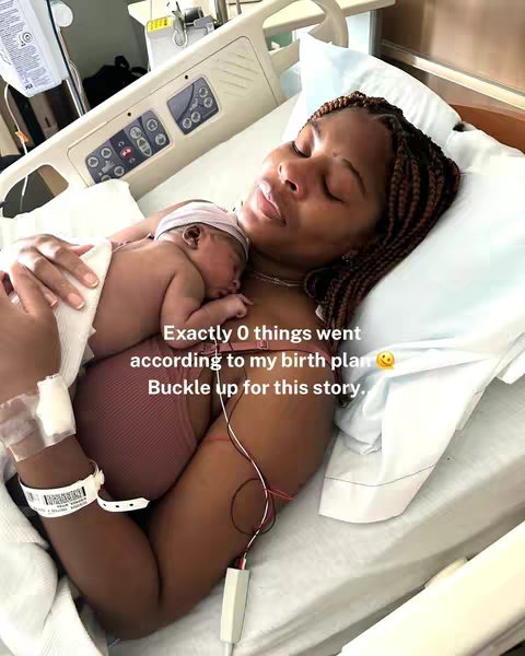 A woman lies in a hospital bed, holding a newborn baby against her chest. The woman has dark skin and is wearing a pinkish-brown top with her hair in braids. The baby is mostly covered but has a pink cap. The background includes hospital equipment, a white sheet, and a pillow. Text is overlaid, expressing a story related to the woman's birth experience.