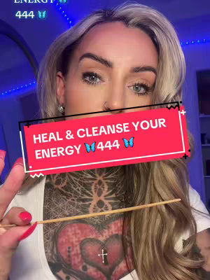 The cover image features a fair-skinned woman with long blonde hair, holding a thin stick with one hand and making a peace sign with the other. A red rectangle with white text overlay across the image says: "HEAL & CLEANSE YOUR ENERGY 🦋 444 🦋". Her chest has a tattoo with a heart and cross.