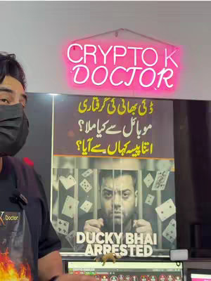 The cover image shows a person in a mask and a black shirt in front of a poster featuring a man behind bars, along with a sign with text in Urdu and English. The background includes a pink neon sign and some computer monitors.