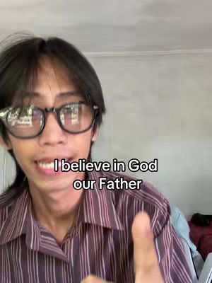 A young man with glasses and a button-down shirt smiles at the camera with a thumbs up, and the text overlay reads "I believe in God our Father."