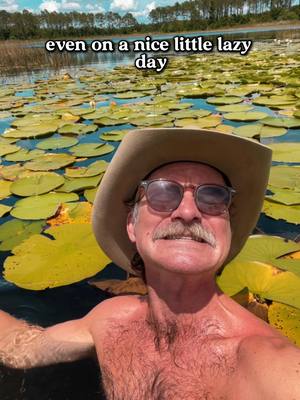 A man is in a body of water surrounded by lily pads, wearing sunglasses and a hat, with text overlayed at the top. The image has a natural, outdoor setting on a sunny day.