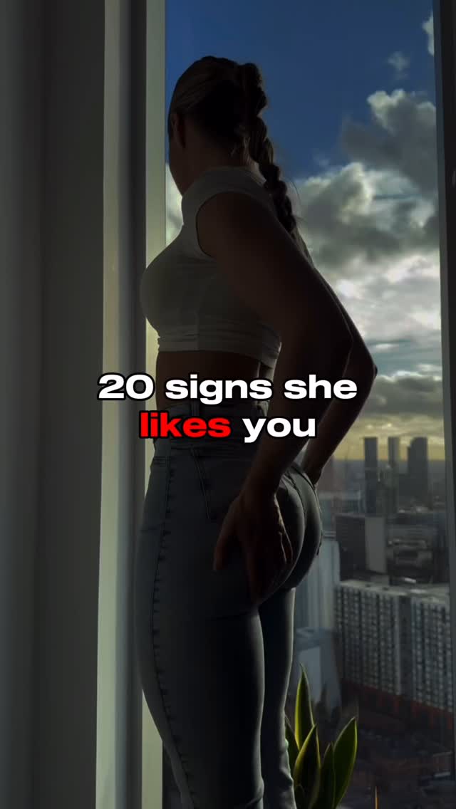 A woman is shown from the side, partially visible, looking out a window. The background includes a cityscape viewed through the window, suggesting a modern or urban setting. Text overlays are present on the image.