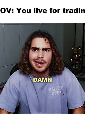 A man with curly hair is in the center of the frame, looking slightly to the side with a surprised expression. The text "DAMN" is in a yellow box toward the bottom of the image. A sign that says gallery dept is slightly below that.  The background is blurry and out of focus.