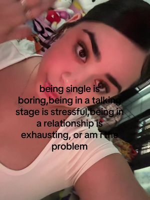 A selfie-style shot focusing on a person's face, appearing to be taken from a low angle. The person has dark hair pulled back, with visible eyebrows and eye makeup. The background is slightly blurred, with what appears to be a stuffed animal and patterned fabric. Overlayed text provides a caption addressing relationship issues.