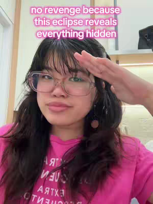 A woman with glasses smiles, raising her hand to her forehead in a salute, with an overlay text on the image.