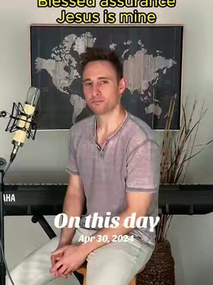 A man sits on a stool in front of a keyboard and microphone, with a world map in the background. Overlayed text reads "Blessed assurance Jesus is mine" and "On this day Apr 30, 2024."