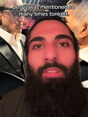 A man with a dark beard is speaking into the camera. A text overlay stating, 'Jesus was mentioned so many times tonight.' appears over his head. There are two people in the background next to the man.