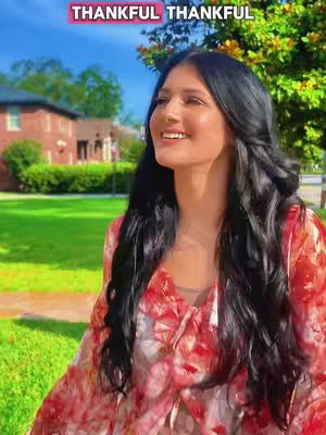 The cover image shows a woman looking upwards slightly to the right of the frame. She has long, dark hair. She is smiling while standing in front of a green lawn with a brick building in the background, and a few trees. The photo has an overall bright and sunny vibe.
