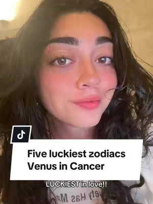 A selfie-style video cover image featuring a woman with dark hair and brown eyes. The woman has a gentle smile and is looking towards the camera. A white text box overlays the lower part of the image, displaying the headline "Five luckiest zodiacs Venus in Cancer", and below the text it reads "LUCKIEST in love!!". The TikTok logo is in the bottom left.