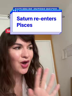 A selfie-style shot featuring a woman with dark hair and a white top. Text overlay appears at top over a blue box saying 'Saturn re-enters Pisces'. The woman has her hand out, looking offscreen and speaking.