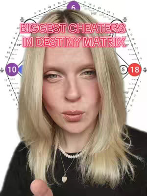 The cover image features a woman in a close-up shot, set and composed for a vertical video format. The background suggests a plain, likely white or light-colored surface. The foreground is dominated by the woman, who has light skin, long blonde hair framing her face, and is wearing a black top with a delicate necklace featuring a heart pendant. She has expressive eyes and is looking towards the camera with a slightly pursed expression, with a light pink lipstick. In the center of the image is a text overlay, in pink and white over her head, reading "BIGGEST CHEATERS IN DESTINY MATRIX," overlaid on a background of a diagram of numbered circles and lines that look like a destiny matrix chart. The overall composition is simple, focusing on the woman's face and the explanatory superimposed text.