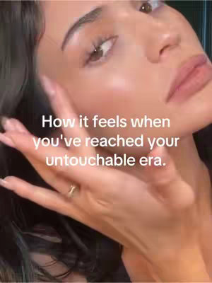 Close-up shot of a woman's face with text overlay. The woman has dark hair and is touching her face with her hand. The text overlay is in white and says "How it feels when you've reached your untouchable era."