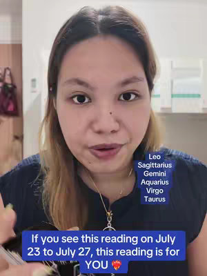 A woman with light skin and long brown hair looks directly at the viewer, with text overlays in the image. She is wearing a dark blue top and a gold necklace. Text overlays on the screen provide information about astrological signs.