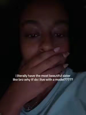 A close-up shot of a person's face with their hand covering their mouth, implying surprise or a confidential reveal. The image has a dark background creating a cinematic effect, with the light source likely coming from the front. Visible text appears in the image.