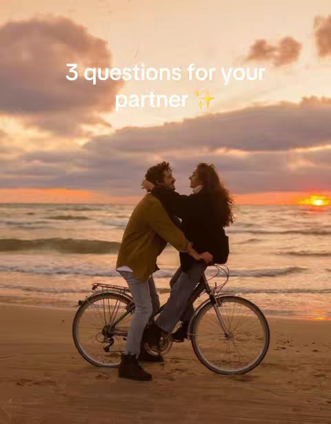 A couple is riding a bike on the beach at sunset. The sun is setting over the ocean, creating a beautiful golden-orange glow in the sky. The text overlay reads "3 questions for your partner".