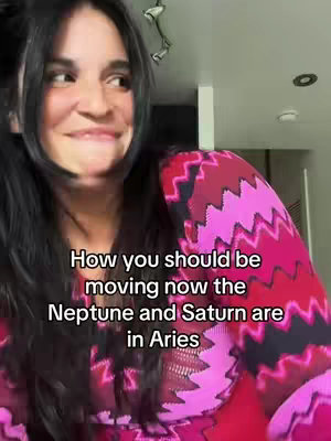 A woman with long black hair and a patterned top looks to her left, slightly smiling. Overlay text reads 'How you should be moving now the Neptune and Saturn are in Aries.' The background is a plain white wall.