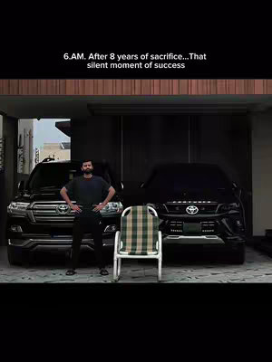 A man stands in front of two black SUVs and a chair in a garage-like setting. Text overlays read the time and a short message.